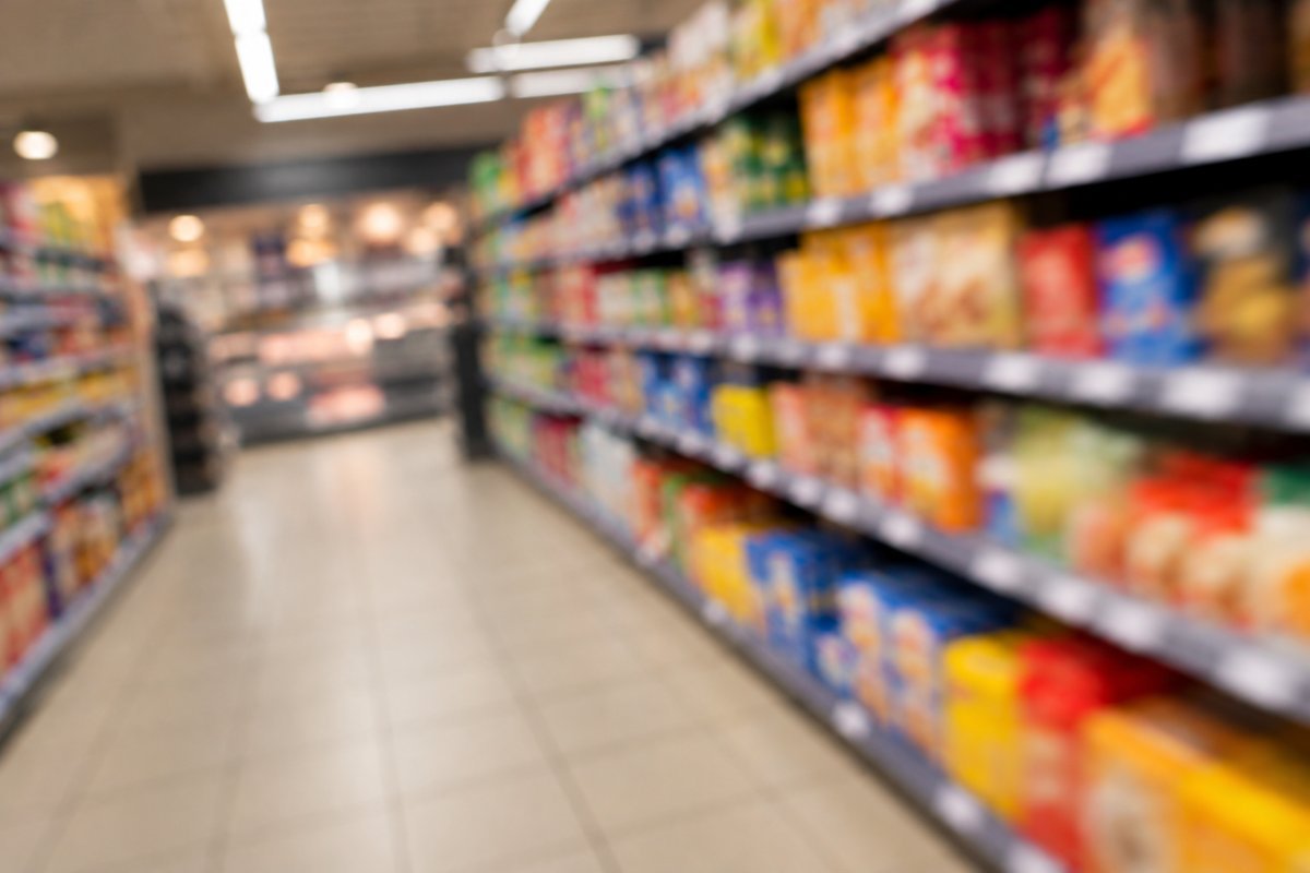 Ein unscharf fotografierter Supermarktgang mit Regalen voller bunter Packungen.
